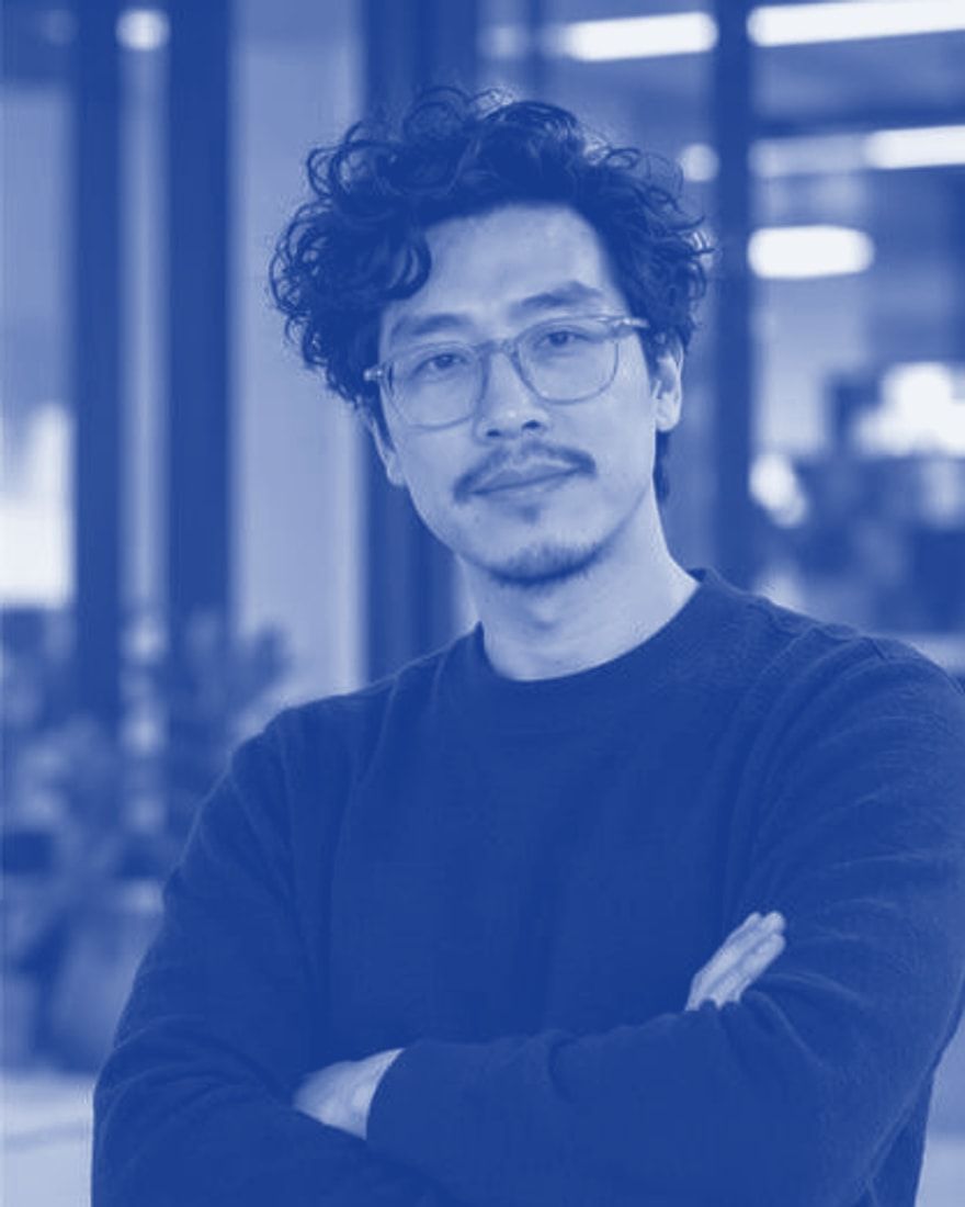 Kam Cheng in an office, arms crossed, smiling slightly